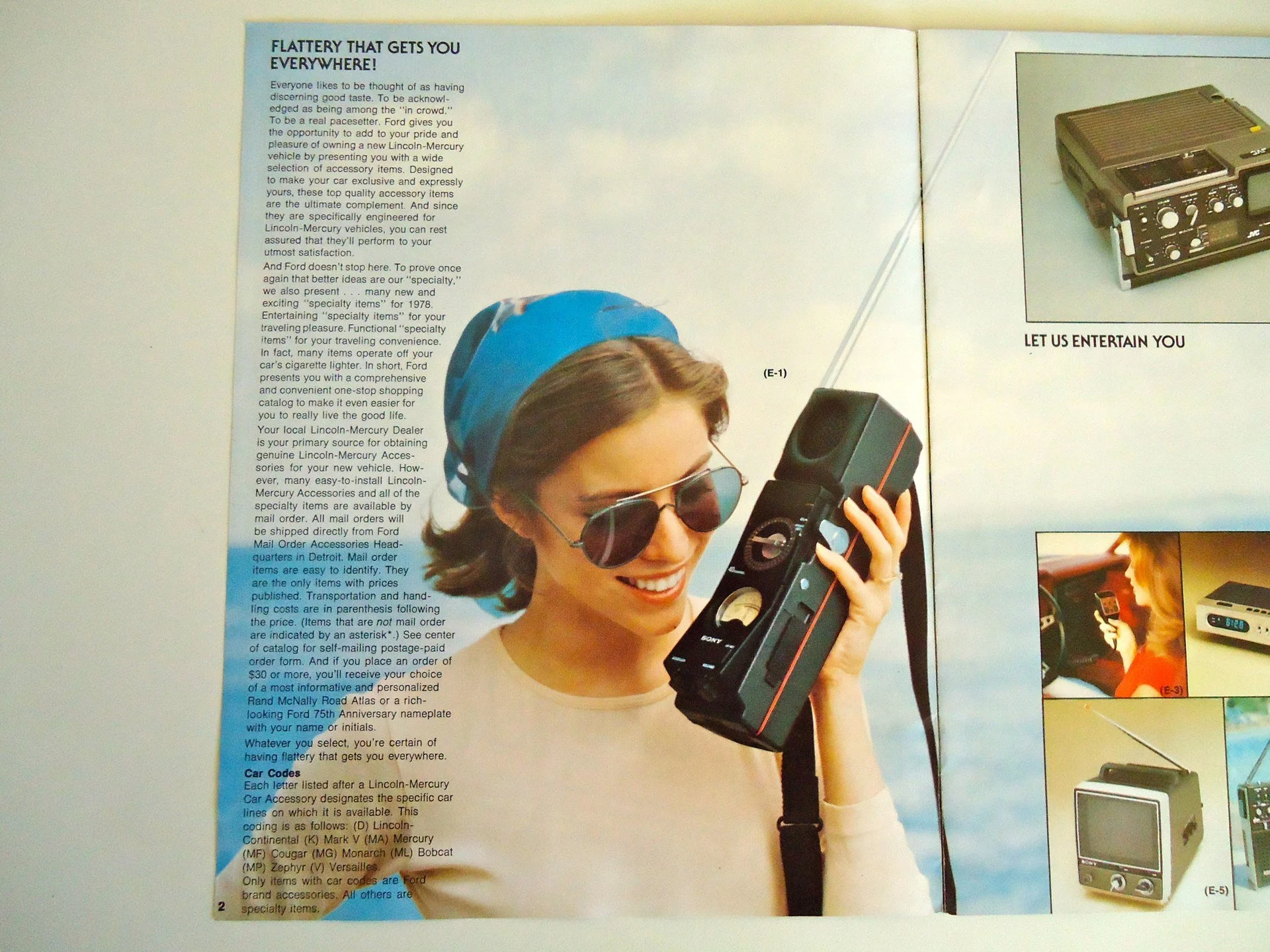 A woman wearing sunglasses and a blue head wrap is smiling and holding a vintage portable radio or cassette player with an antenna.