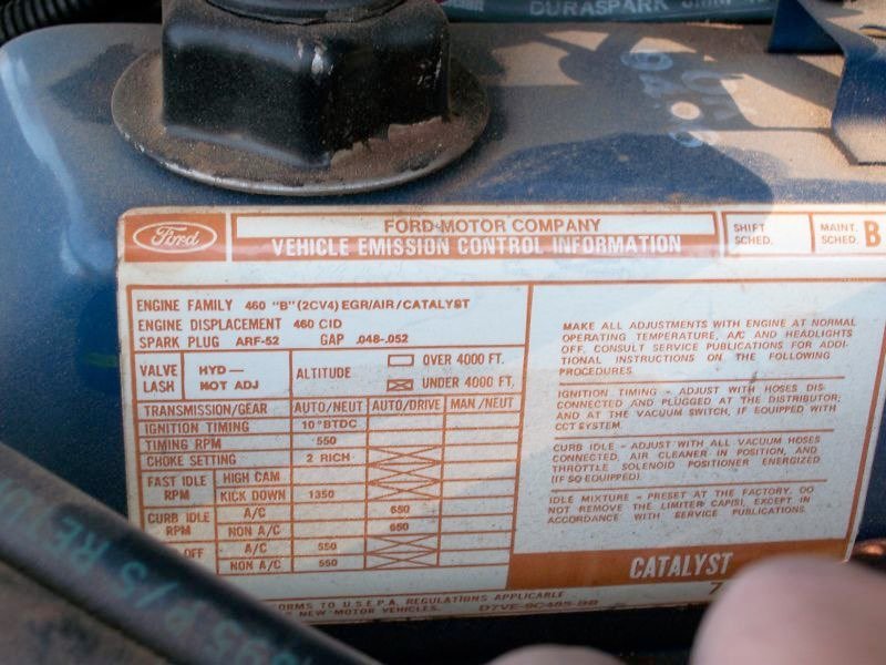 Close-up of a vehicle emission control information label on a Ford vehicle engine compartment, showing engine, transmission, and ignition specifications.