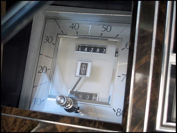 Close-up of a vintage car dashboard speedometer and odometer with chrome accents.