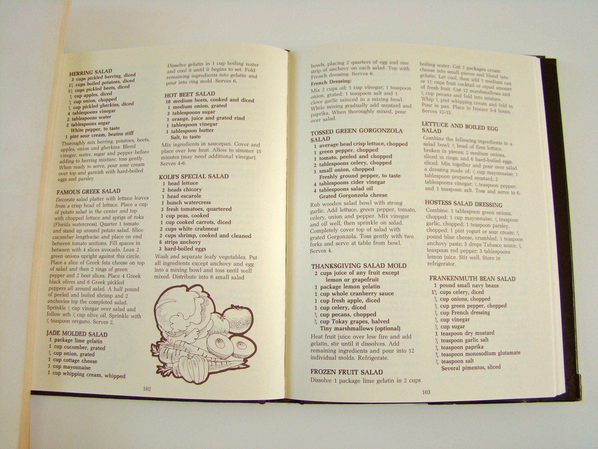 Open cookbook page showing various salad recipes, including Herring Salad, Famous Greek Salad, Hot Beet Salad, Kolb's Special Salad, Jade Molded Salad, Tossed Green Gorgonzola Salad, Thanksgiving Salad Mold, Frozen Fruit Salad, Lettuce and Boiled Egg