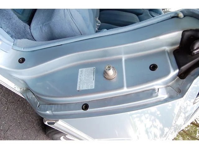 Close-up of a locked car door with a steel lock bolt in the center, no door handle visible.