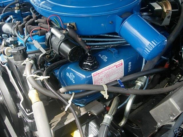 Close-up of a blue engine with various hoses, wires, and mechanical components in a vehicle.