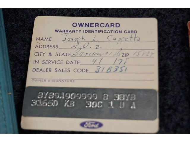 A Ford vehicle's ownercard with handwritten details including the owner's name, address, city, state, ZIP code, service date, and dealer sales code.