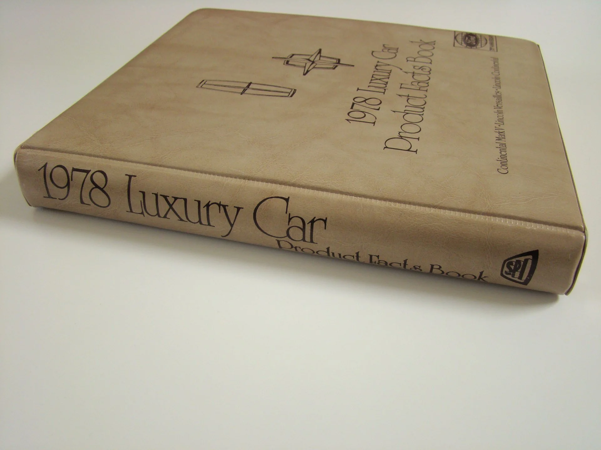 A beige hardcover book titled '1978 Luxury Car Product Facts Book' lying on a white surface.