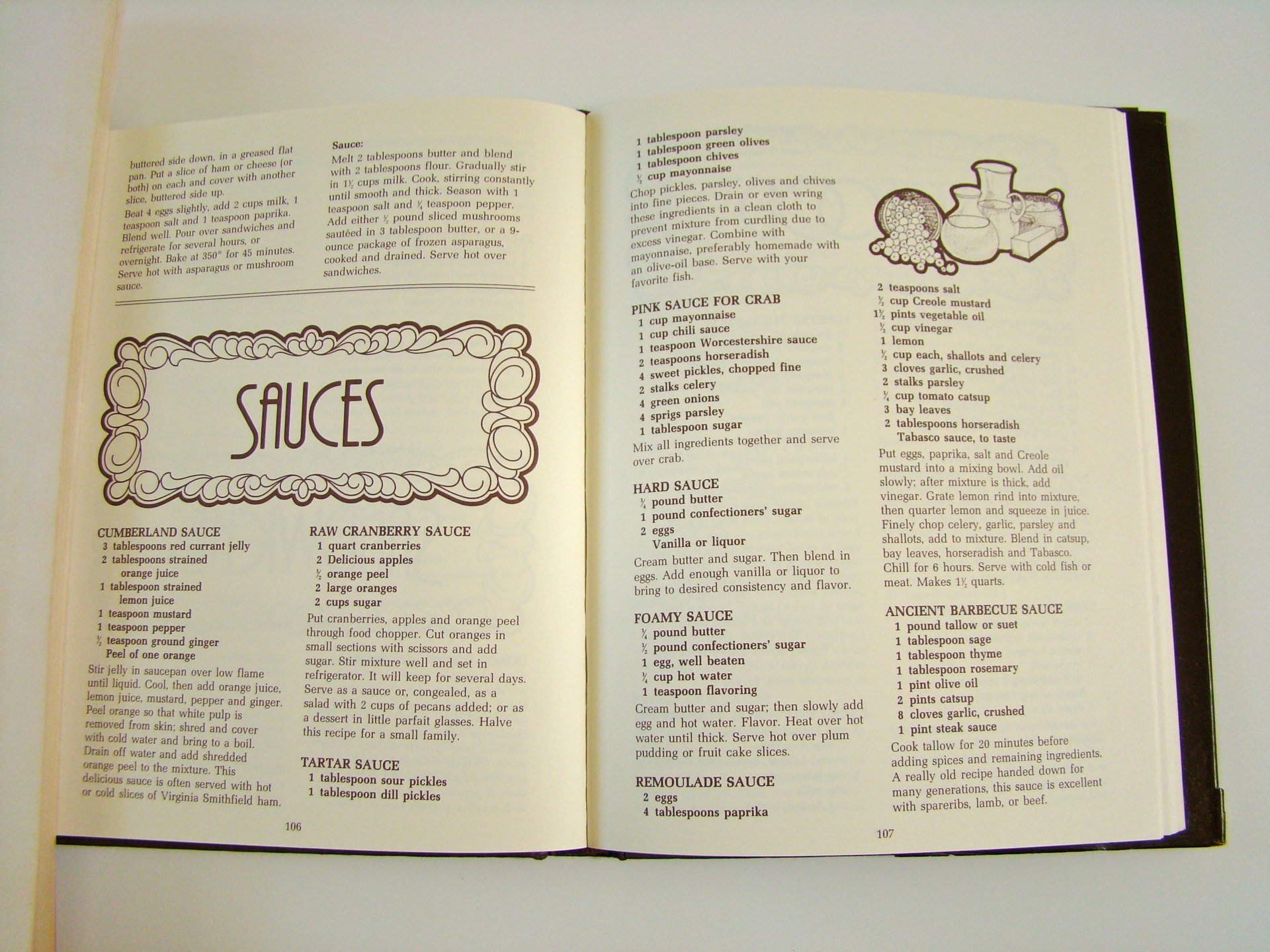 Open cookbook with a page titled 'SAUCES' listing recipes and ingredients for various sauces, including Cumberland, Cranberry, Tartar, Remoulade, Pink Crab, Hard, Foamy, and Barbecue.