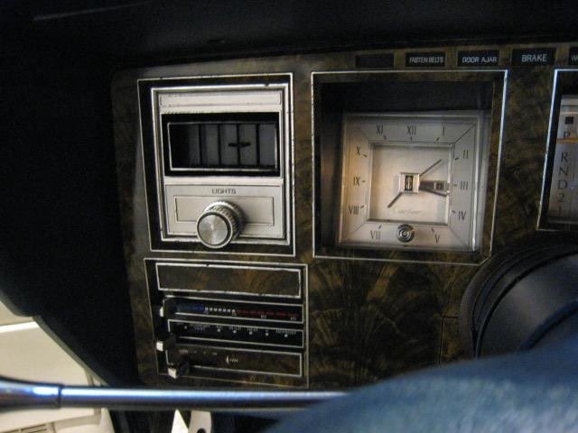 Close-up of vintage car dashboard with clock, radio, and control switches.