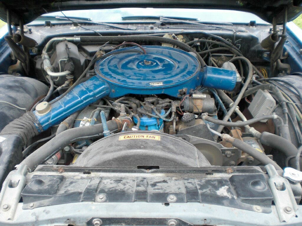 Car engine with blue air cleaner and various hoses and components