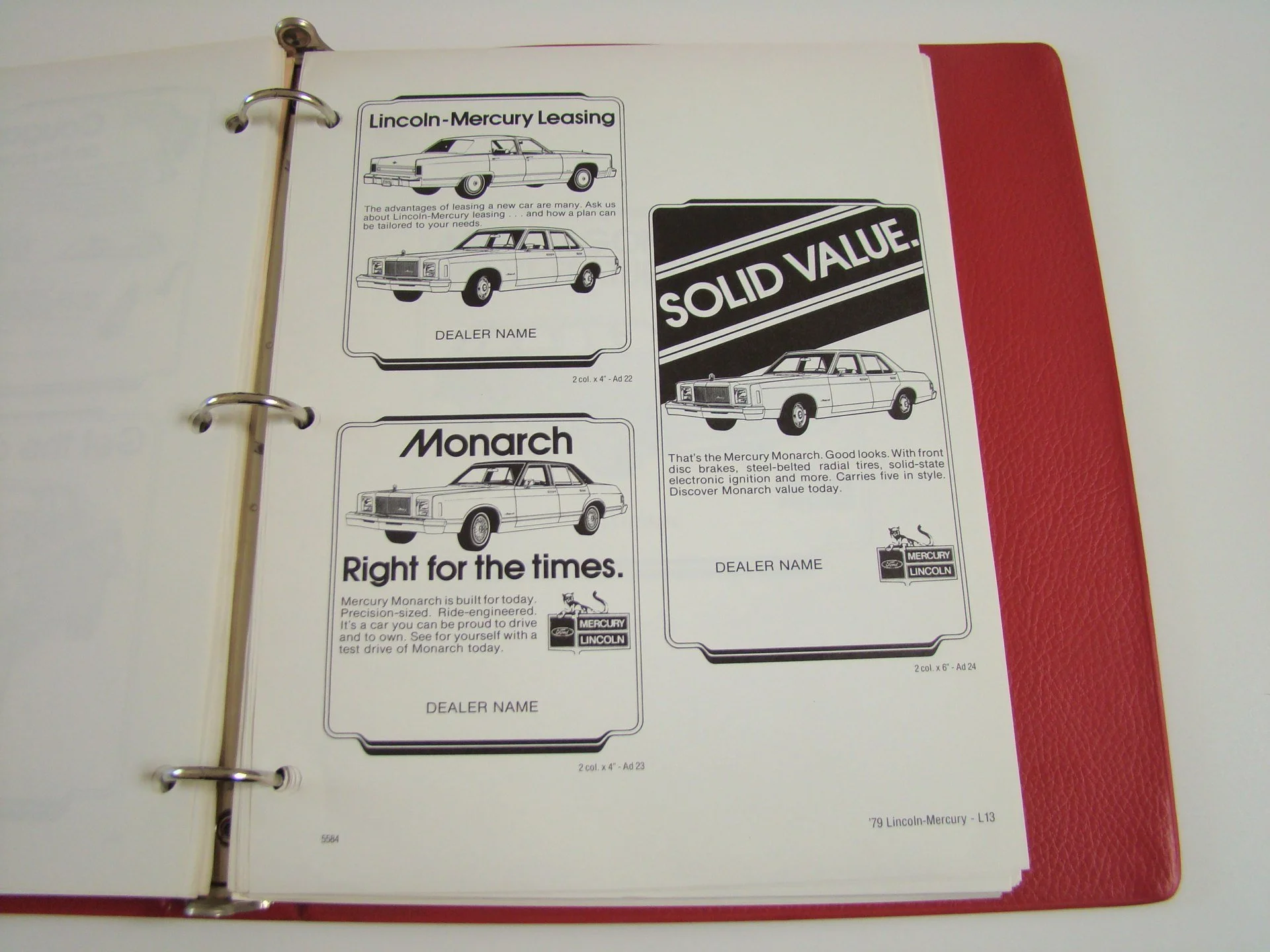 Open binder displaying black and white advertisements for Lincoln-Mercury cars, including models Monarch and Mercury Lincoln, with text and images of the cars.