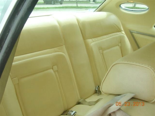 The back seat interior of a vintage car with yellow upholstery.