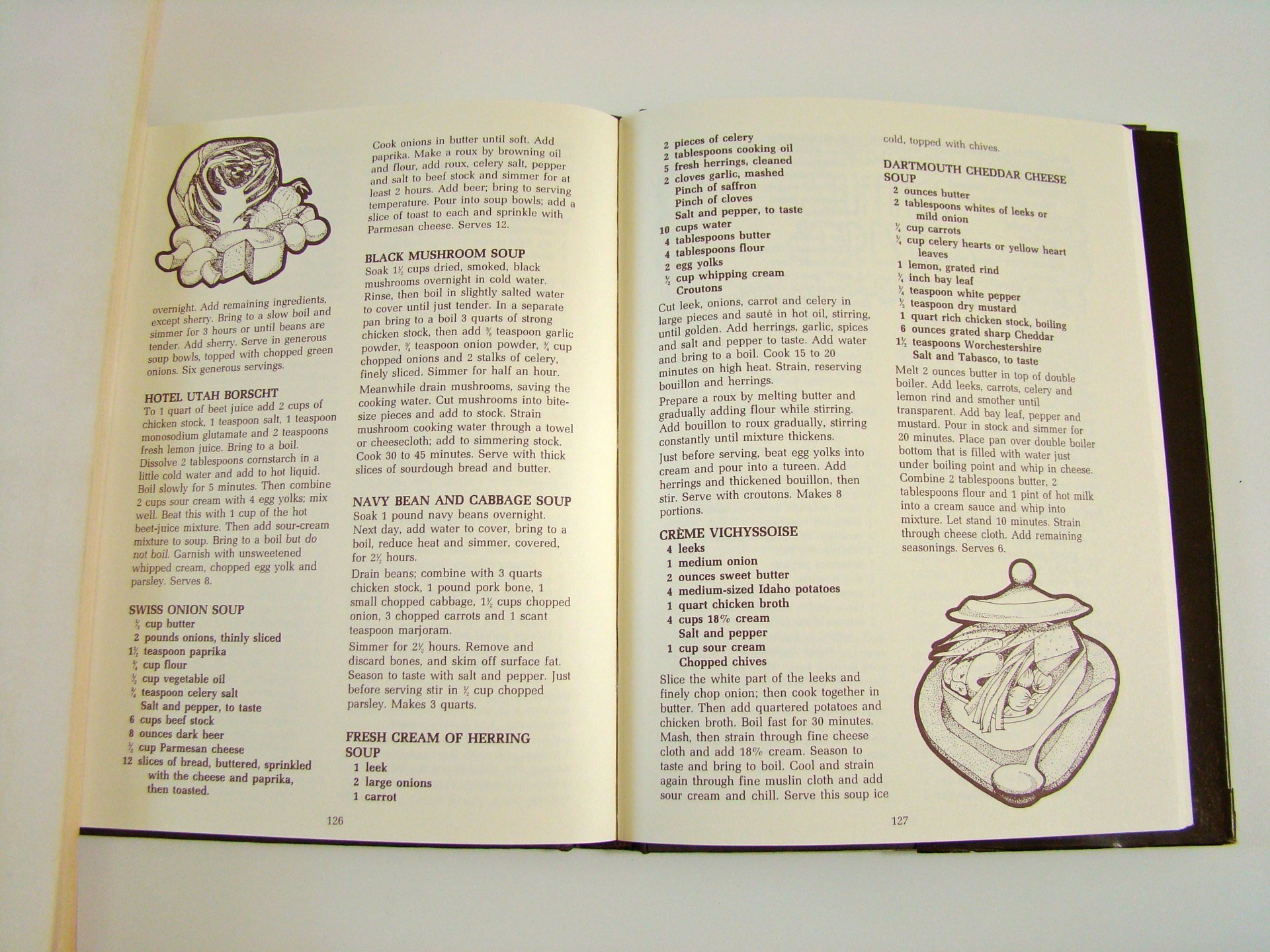 Open cookbook showing recipes for various soups and dishes, including black mushroom soup, hotel Utah Borscht, navy bean and cabbage soup, Swiss onion soup, Dorset Cheddar cheese soup, and Crème Vichyssoise. The pages feature text recipes and a simpl