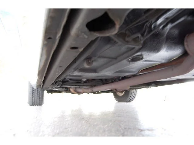 Underneath view of a vehicle showing parts of the exhaust system and suspension.