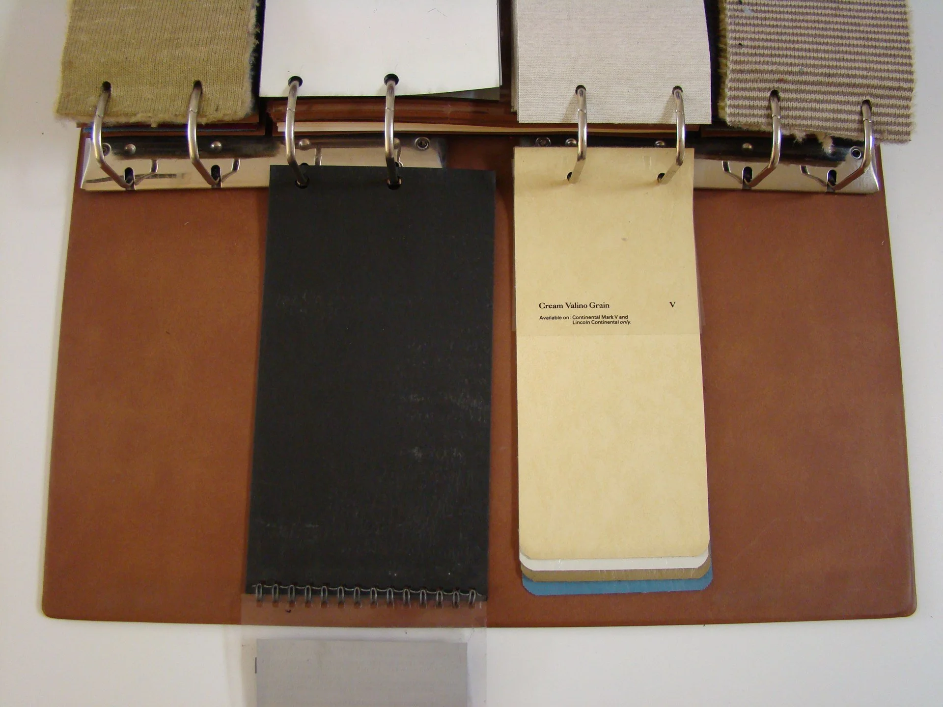Color sample swatches and fabric samples attached to a quick-reference material sample board with metal rings.