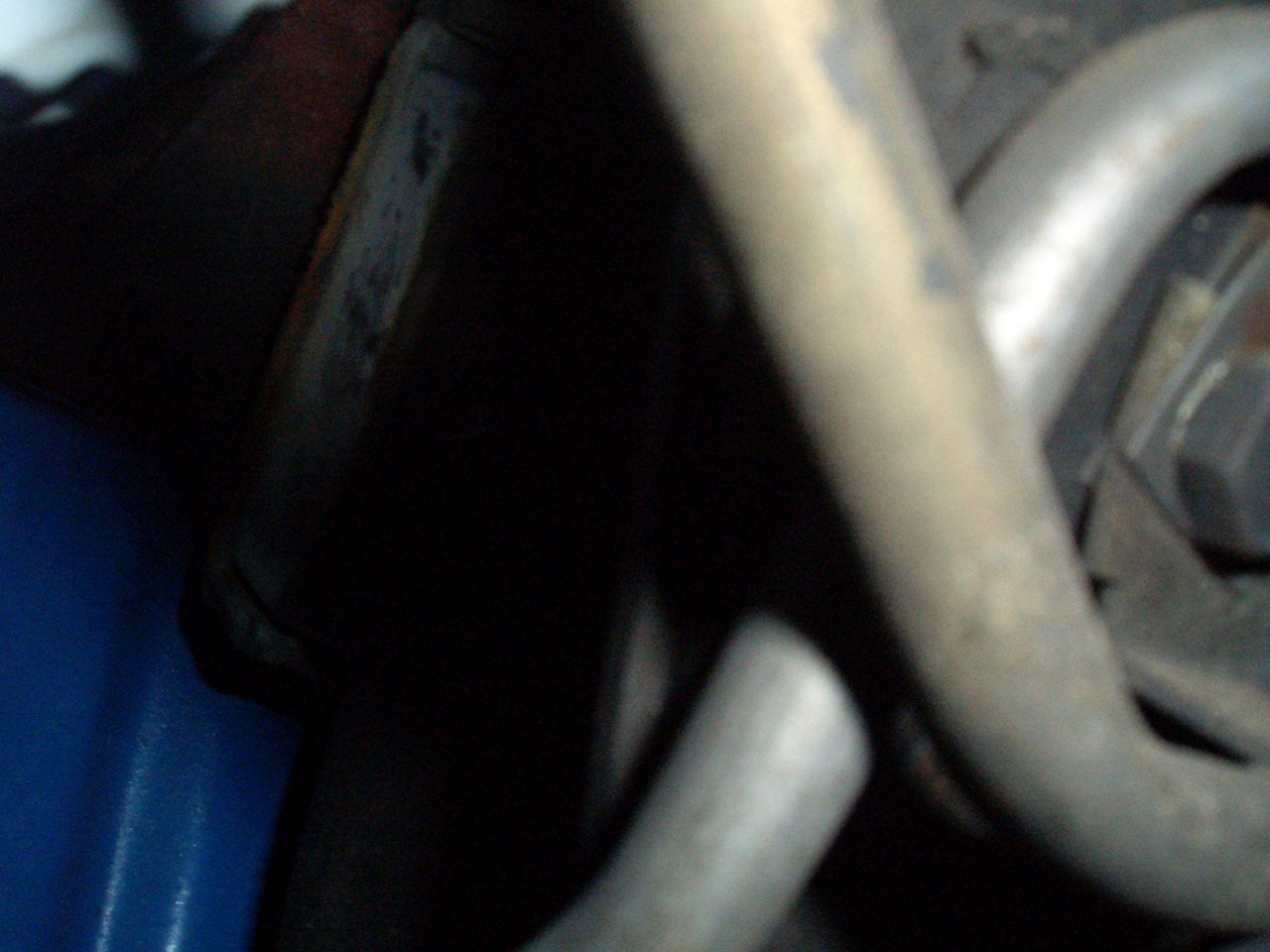Close-up of various metal engine parts, including pipes and a blue engine cover