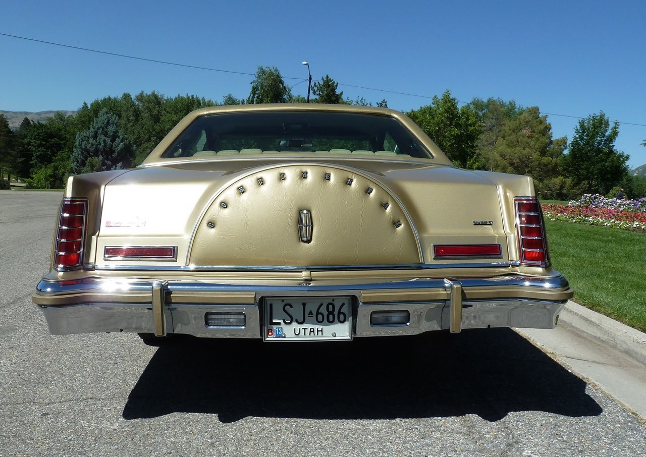Rear view of a vintage Lincoln Continental car with gold exterior, Utah license plate, and a unique spare tire cover with the word "Boundless" on it.