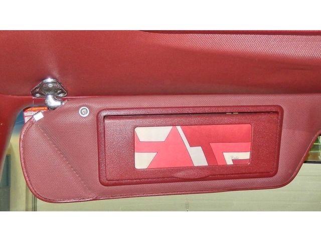 Red emergency exit sign on a car's red interior ceiling, indicating the location of an emergency exit handle.