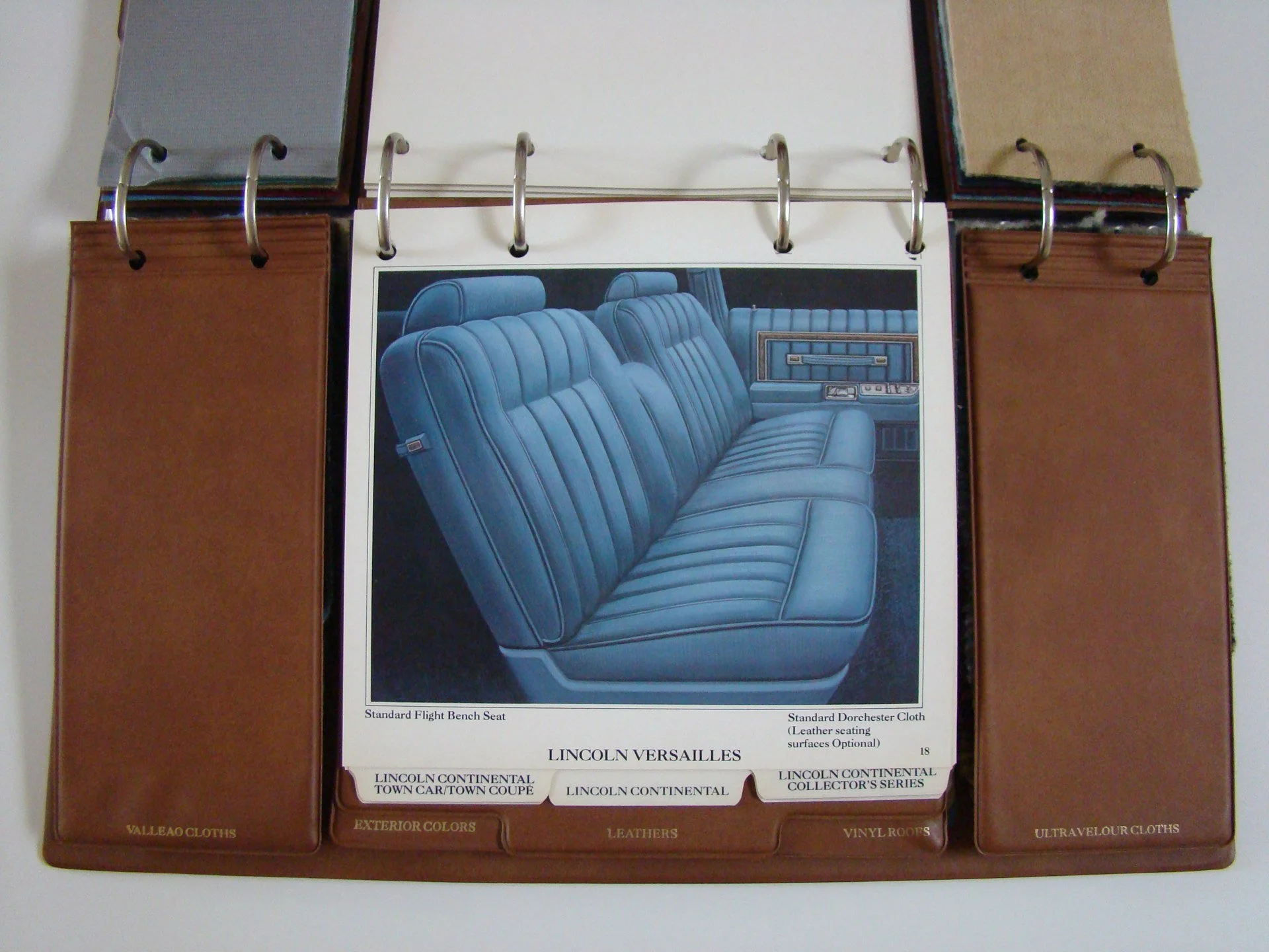Color sample and fabric swatch binder open to page displaying a photo of blue leather seats in a Lincoln Versailles vehicle.