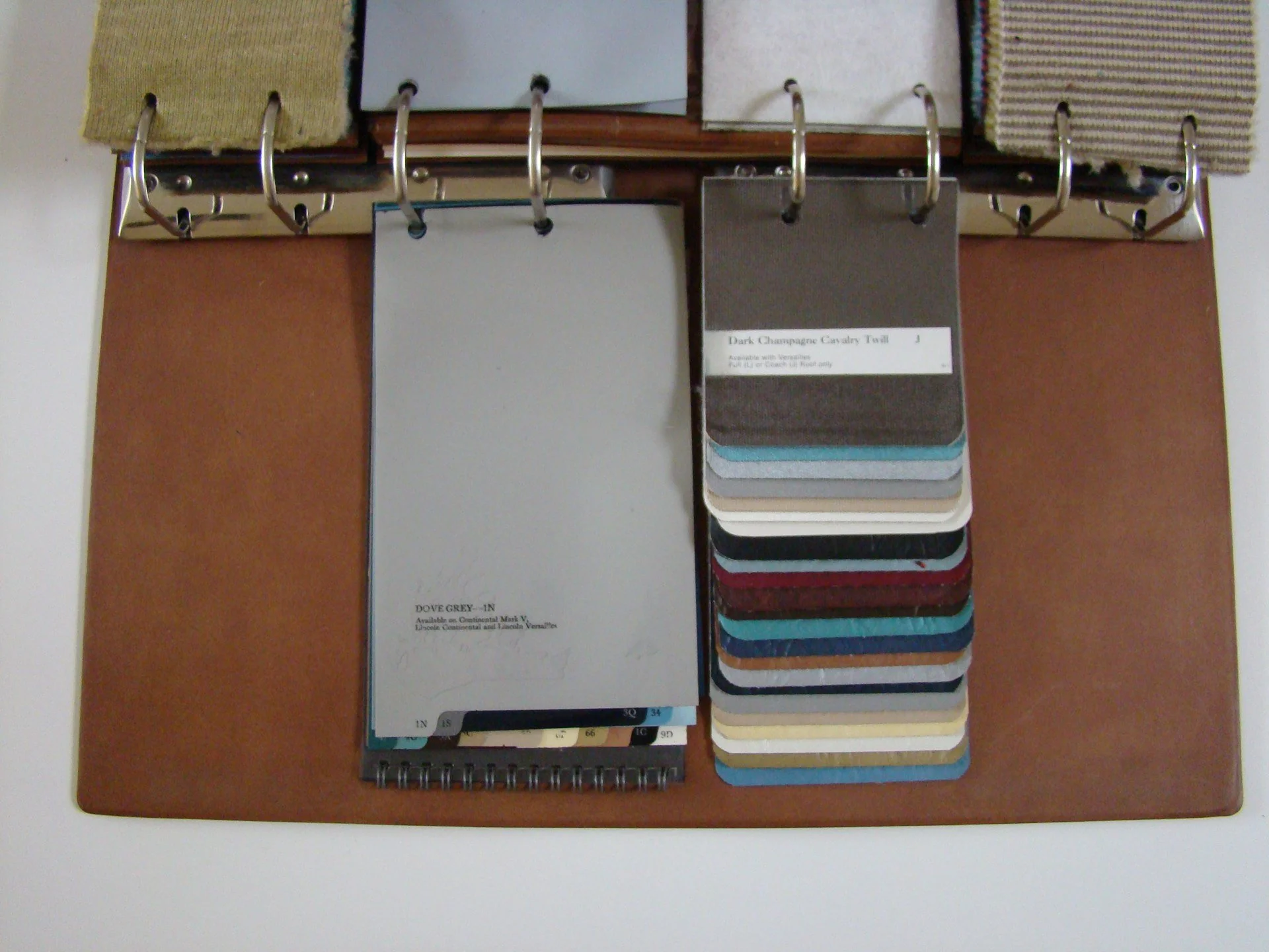 Color swatches and fabric samples in a binder, labeled with names like 'Dark Champagne Cavalry Twill' and 'Dove Grey'.