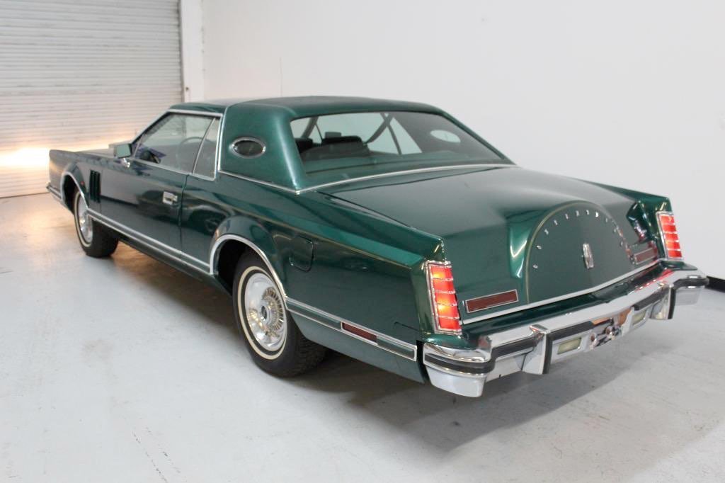 Green vintage Lincoln Continental Mark IV car parked indoors.
