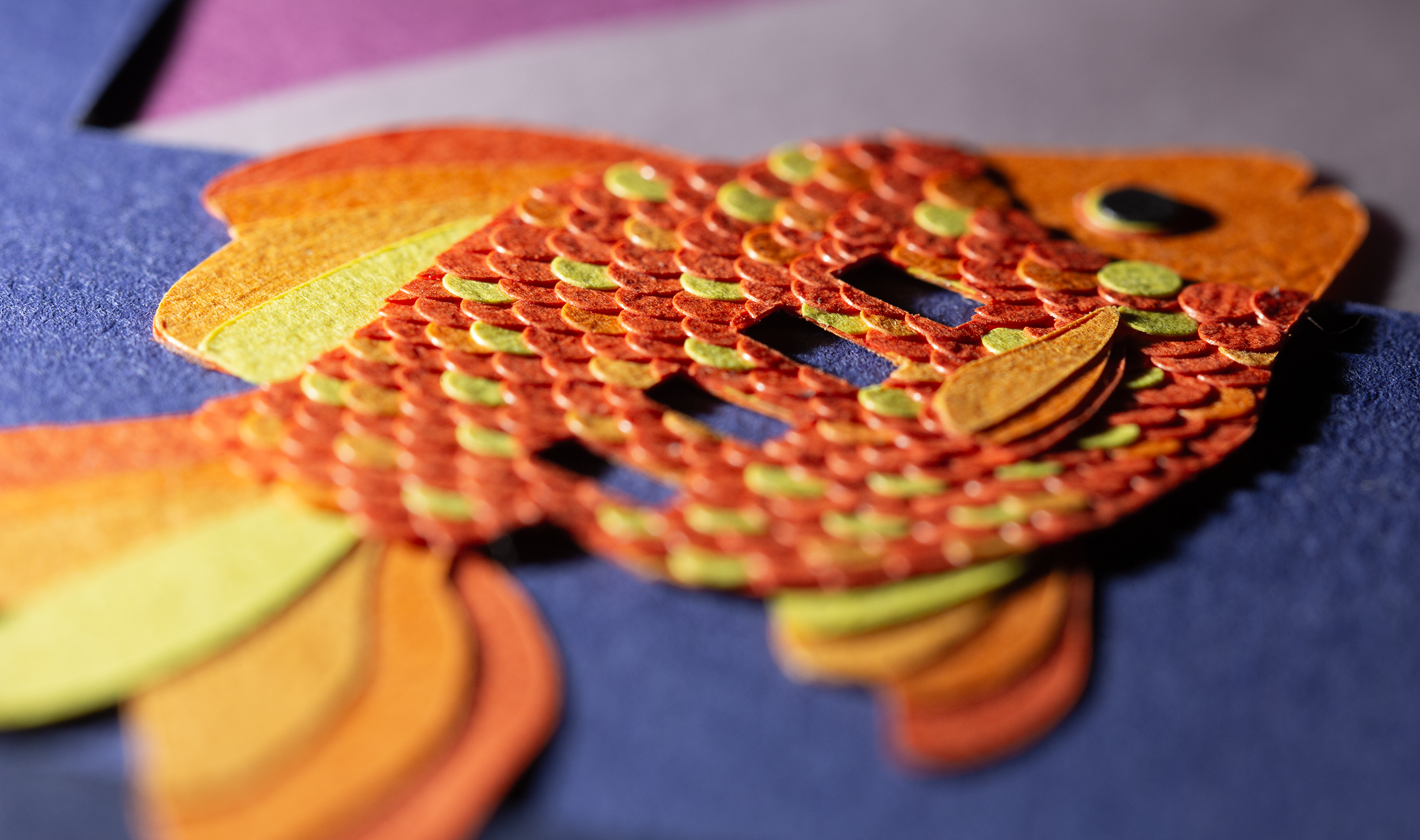 Close-up of a layered paper cut fish with window cutouts resembling a bus.