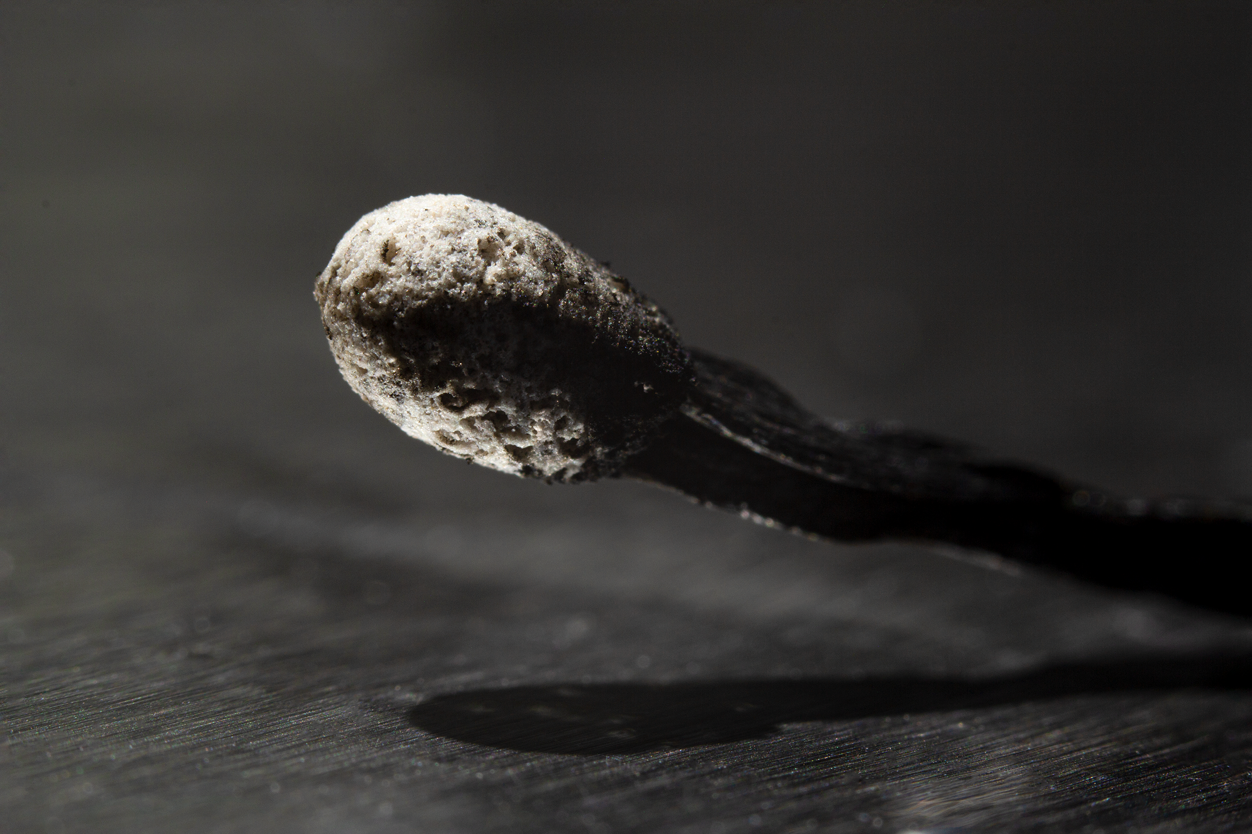 Close-up of a burnt match head resting on foil.