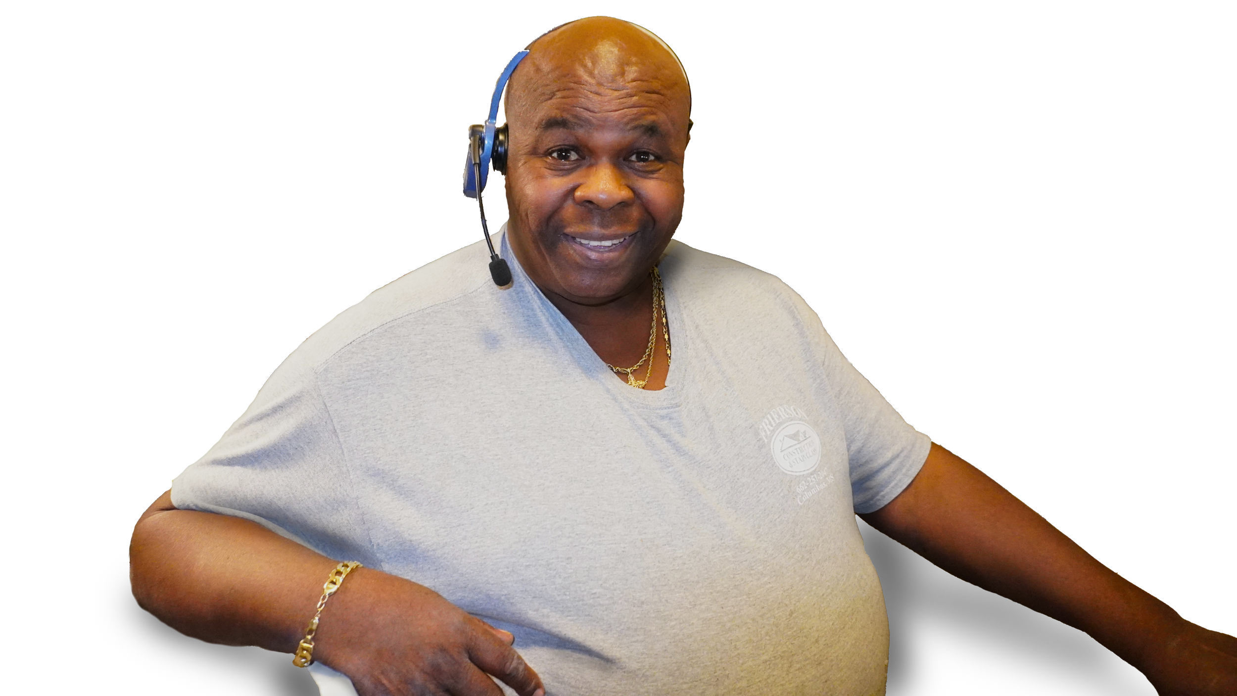 A smiling man wearing a gray T-shirt, a gold chain necklace, a gold bracelet, and a headset with a microphone.