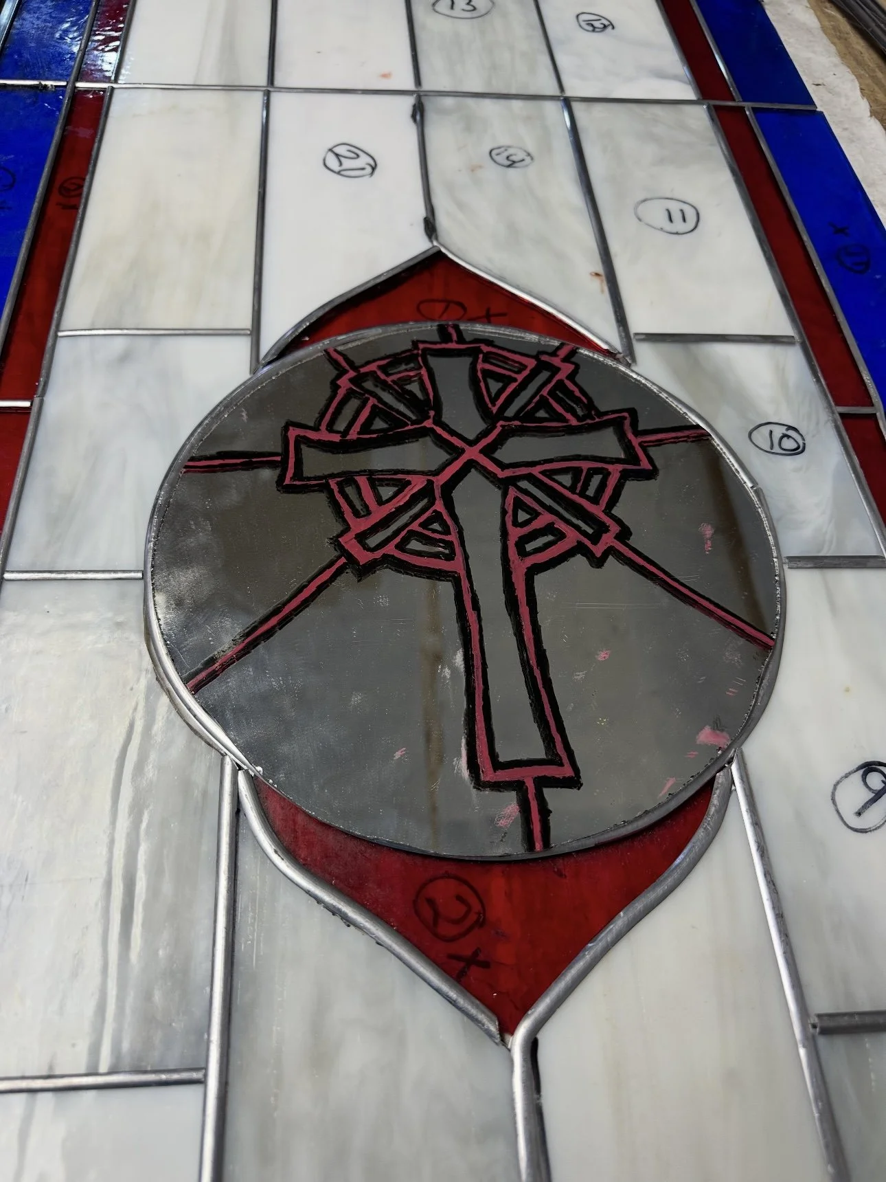 Stained glass church window featuring a black and red Christian cross design.
