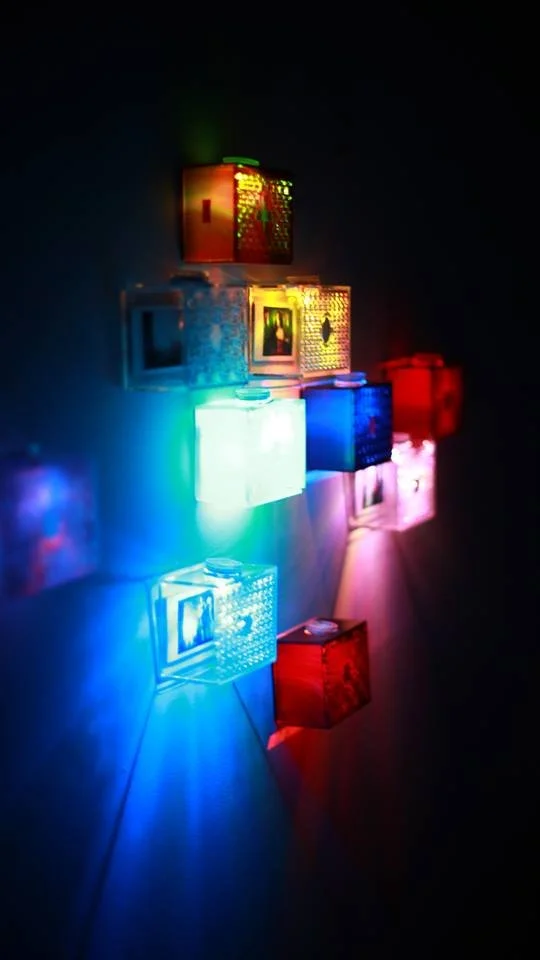 Colorful illuminated cubes mounted on a dark wall display a spectrum of vibrant lights.