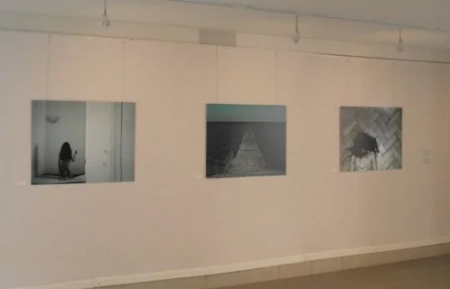 Three black-and-white photographs hung on a white gallery wall.