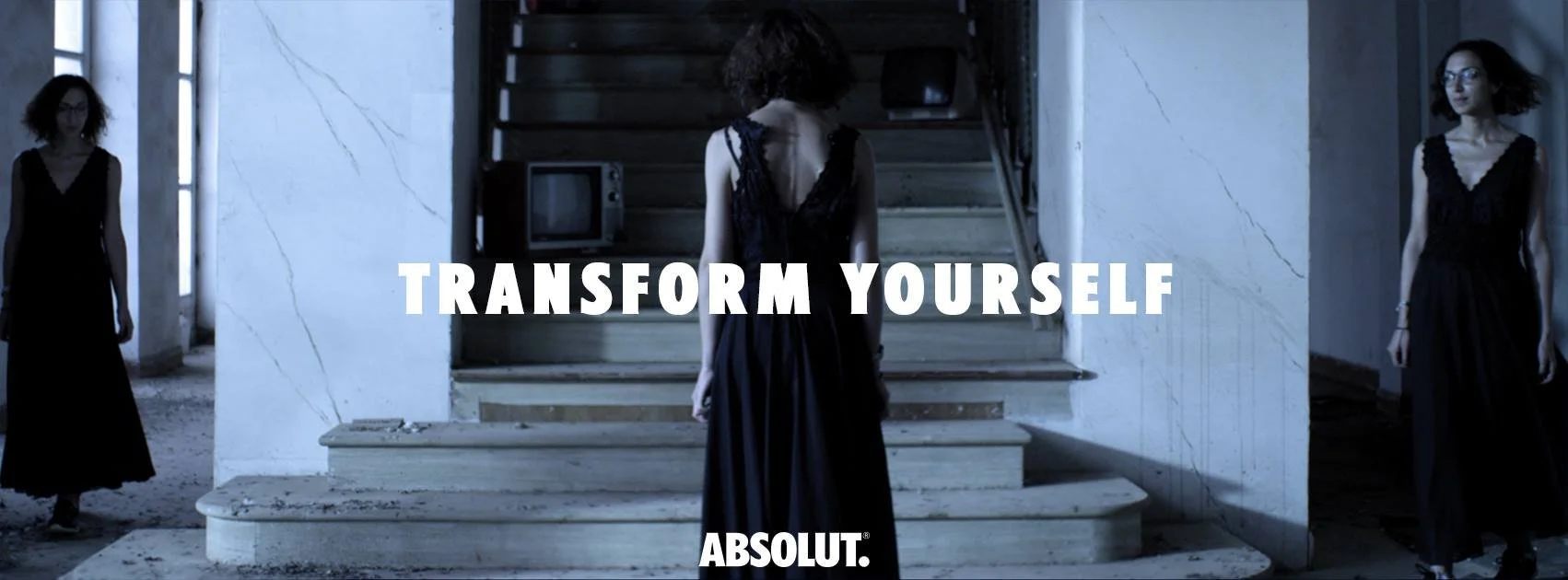 Three women in black dresses standing on marble stairs in an abandoned building, with the text 'Transform Yourself' and the Absolut logo overlayed.