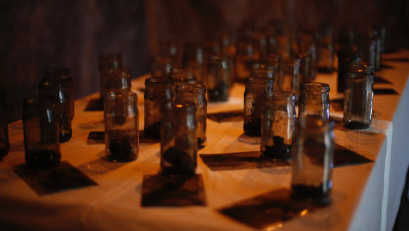 Multiple small glass jars arranged on a table with a warm orange lighting