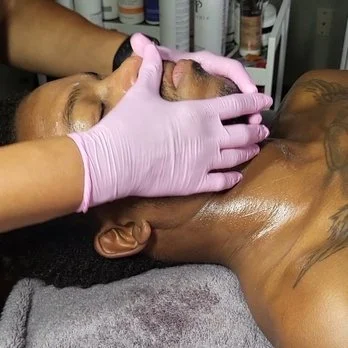 Young African American male relaxing as he receives a facial from a person with pink gloves
