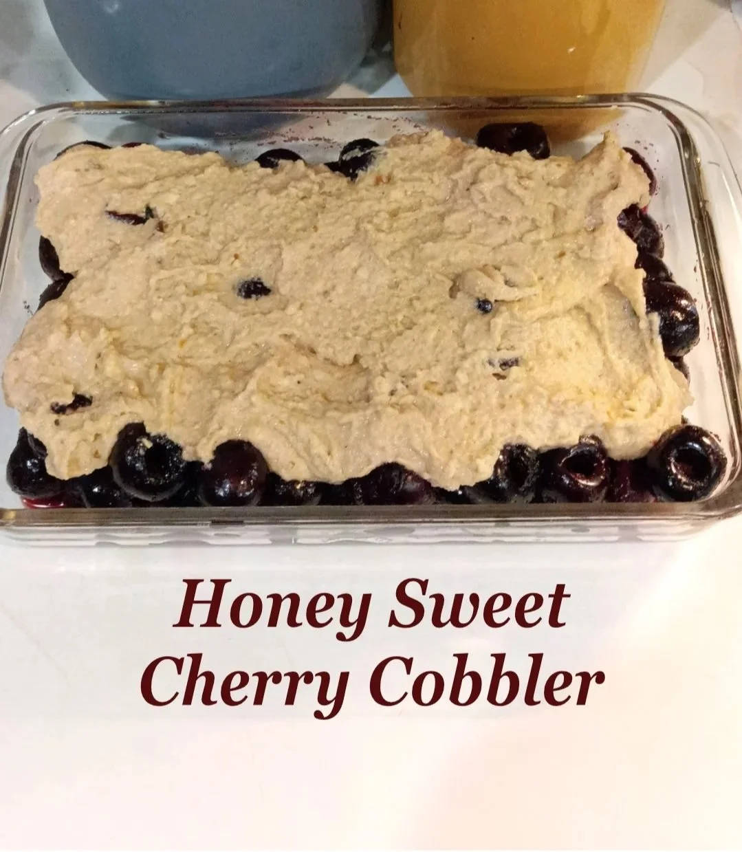 Sweet cherries covered with fresh milled flour cobbler topping in a glass baking dish, ready for the oven.