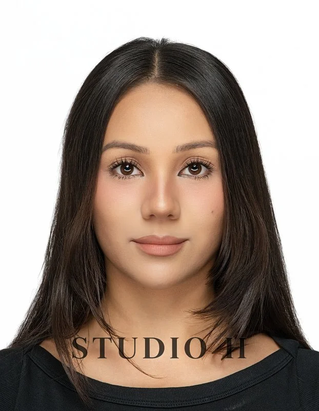 Front view of a young woman with straight dark hair, wearing a black top, against a plain white background.