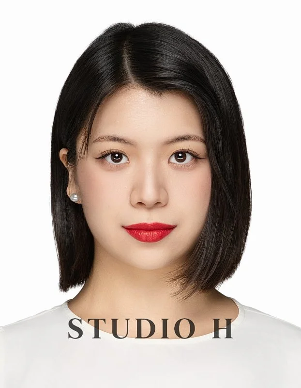 A young woman with short black hair, wearing pearl earrings and red lipstick, against a white background with the text "STUDIO H" at the bottom.