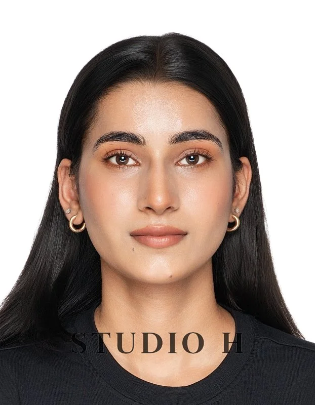 A woman with long black hair, tan skin, wearing gold hoop earrings, and a black shirt, looking directly at the camera against a plain white background. The text 'STUDIO H' is visible at the bottom.