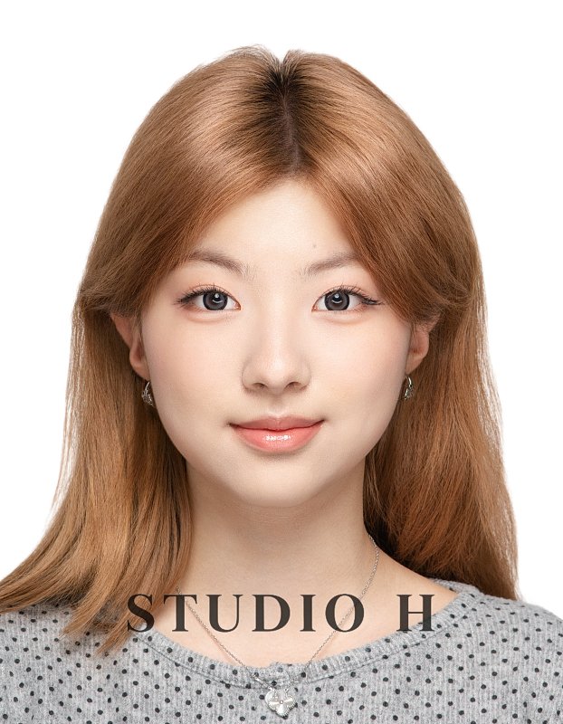 A young woman with shoulder-length light brown hair, hazel eyes, and light makeup, wearing a gray polka-dot top and small earrings, smiling at the camera against a white background.