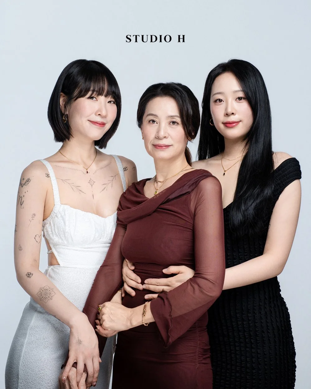 Three women posing together in front of a plain background with the text 'STUDIO H' at the top.