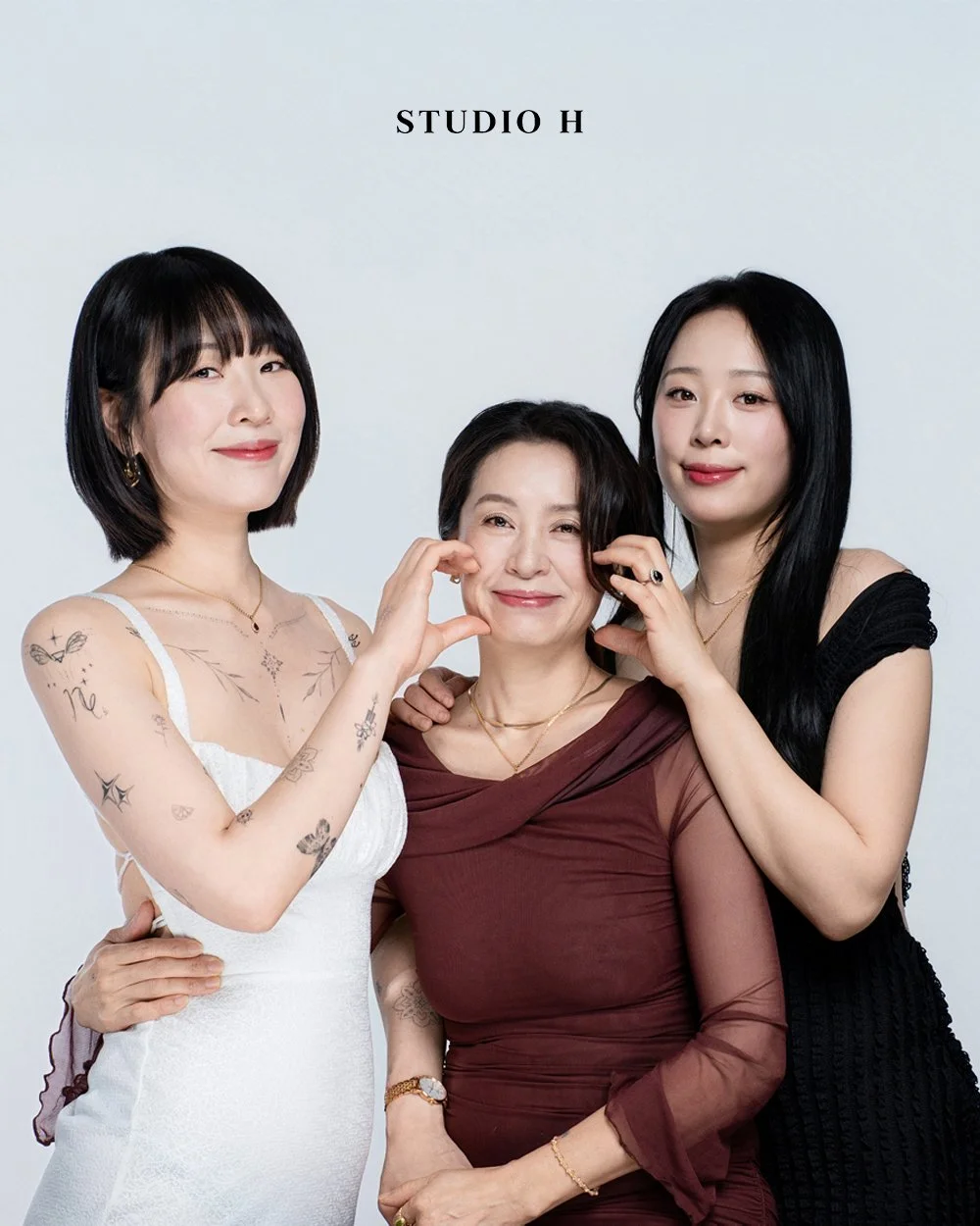 Three women posing together for a studio photo against a white background, with the text 'STUDIO H' above them.