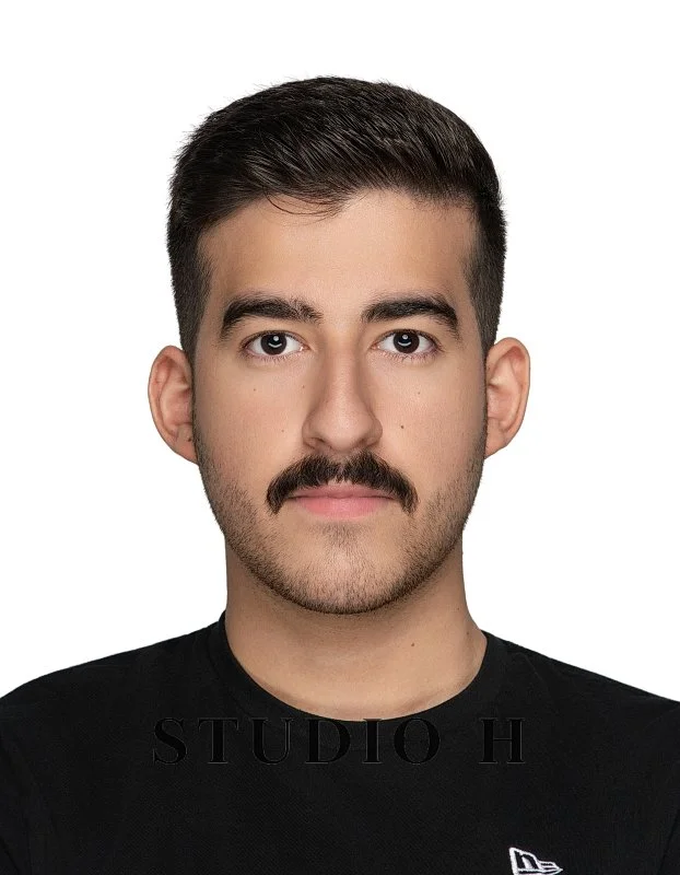 Portrait of a man with short dark hair, a mustache, wearing a black shirt, against a white background.