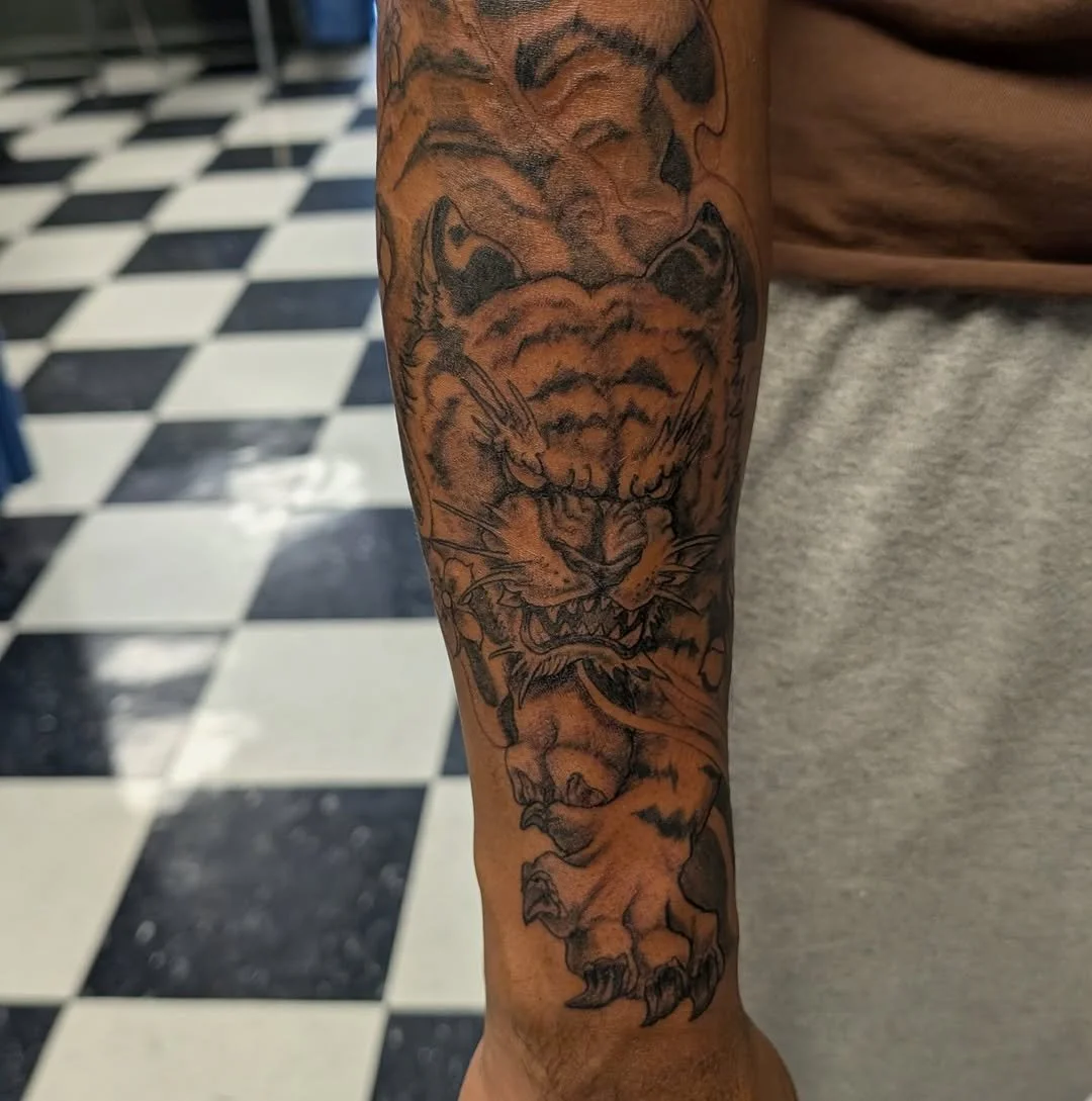 Tattoo of a fierce tiger's face on a person's forearm.