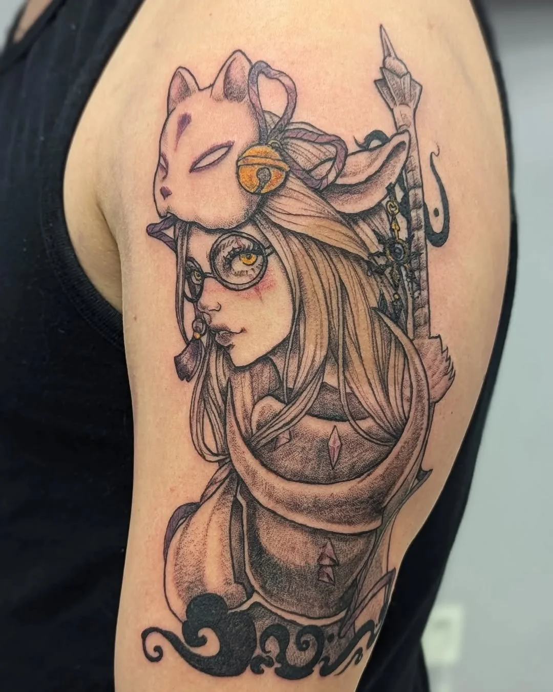 Tattoo of a girl with long hair, eyeglasses, and a focused expression, with a cat wearing a bell on its collar resting on her head, a sword behind her, and a yin-yang symbol on her sleeve.