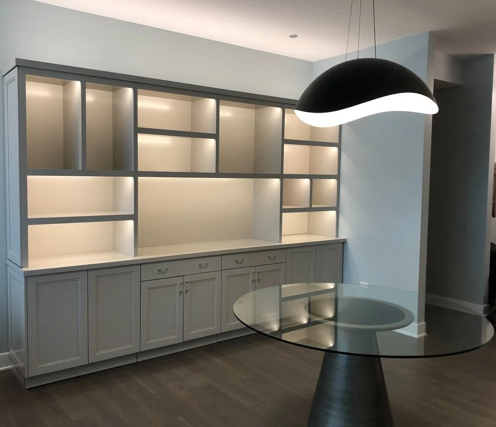 Modern kitchen with built-in white cabinetry, open shelving, and a glass-top table under a black pendant light.