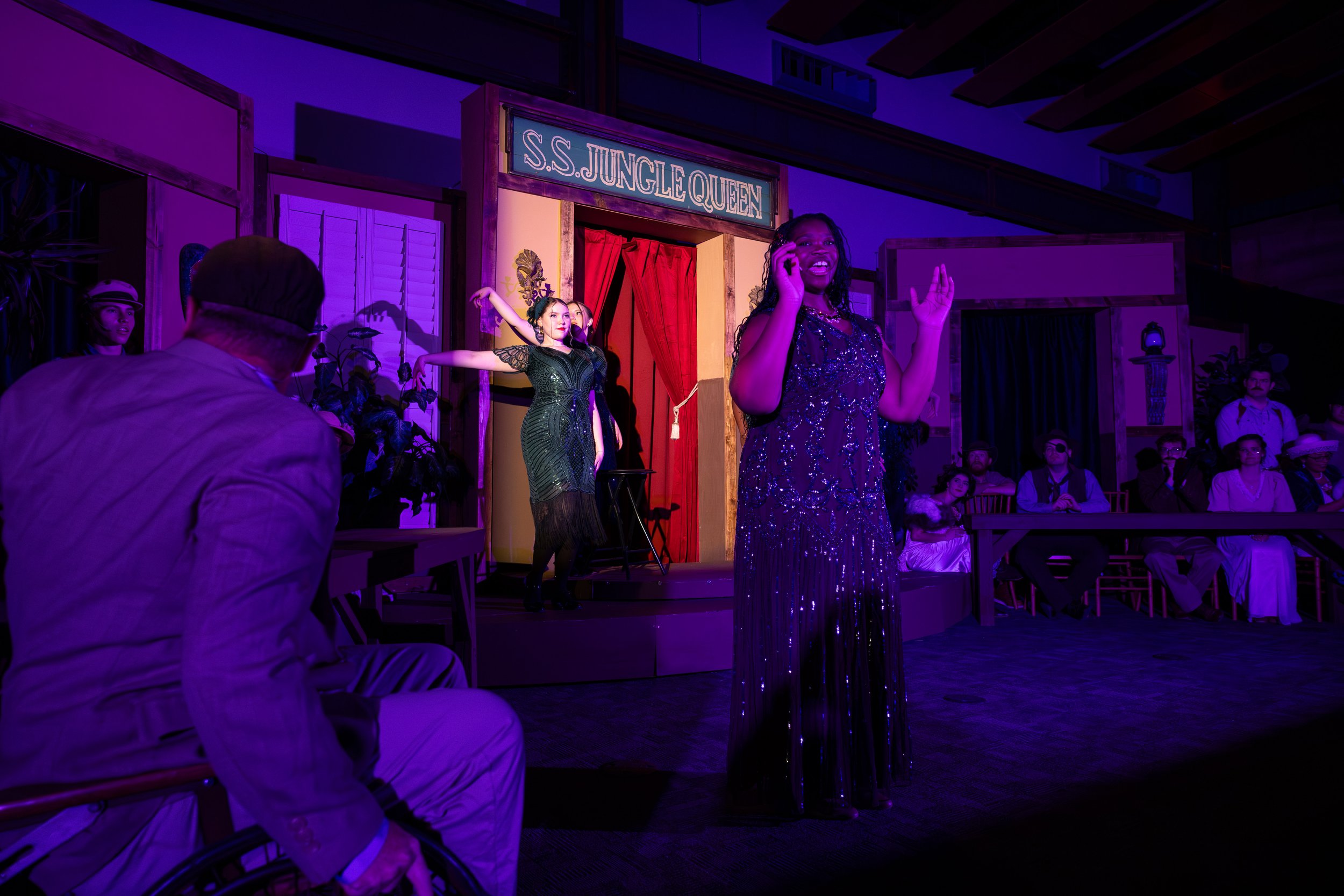 A talented local actress performing a musical number under stage lights during the Broadway Maricopa production of Murder Aboard the S.S. Jungle Queen in Maricopa, Arizona.