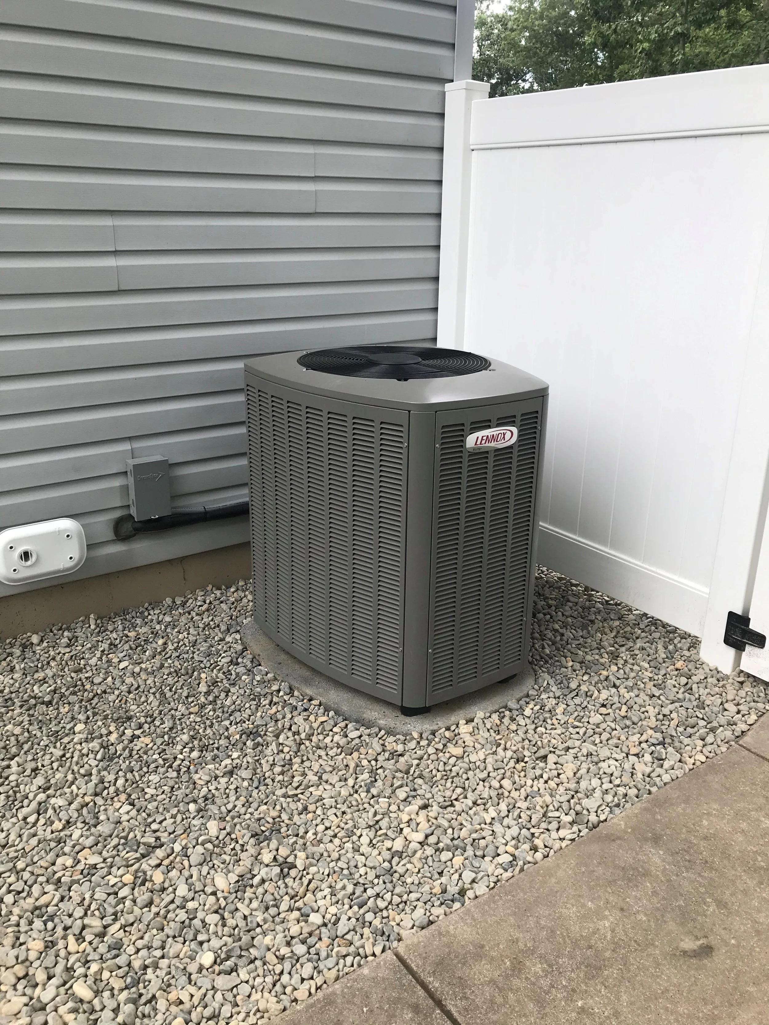 Outdoor Lennox air conditioning unit installed on a concrete pad against a building wall.