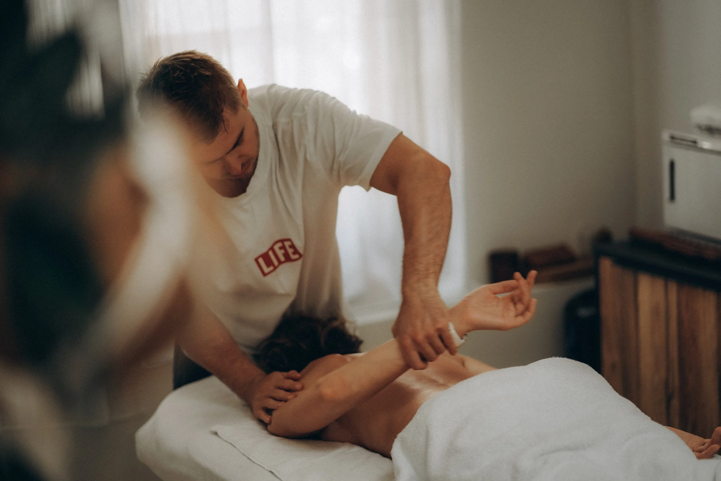 A man giving a massage to a woman lying on a massage table in a room with soft lighting.