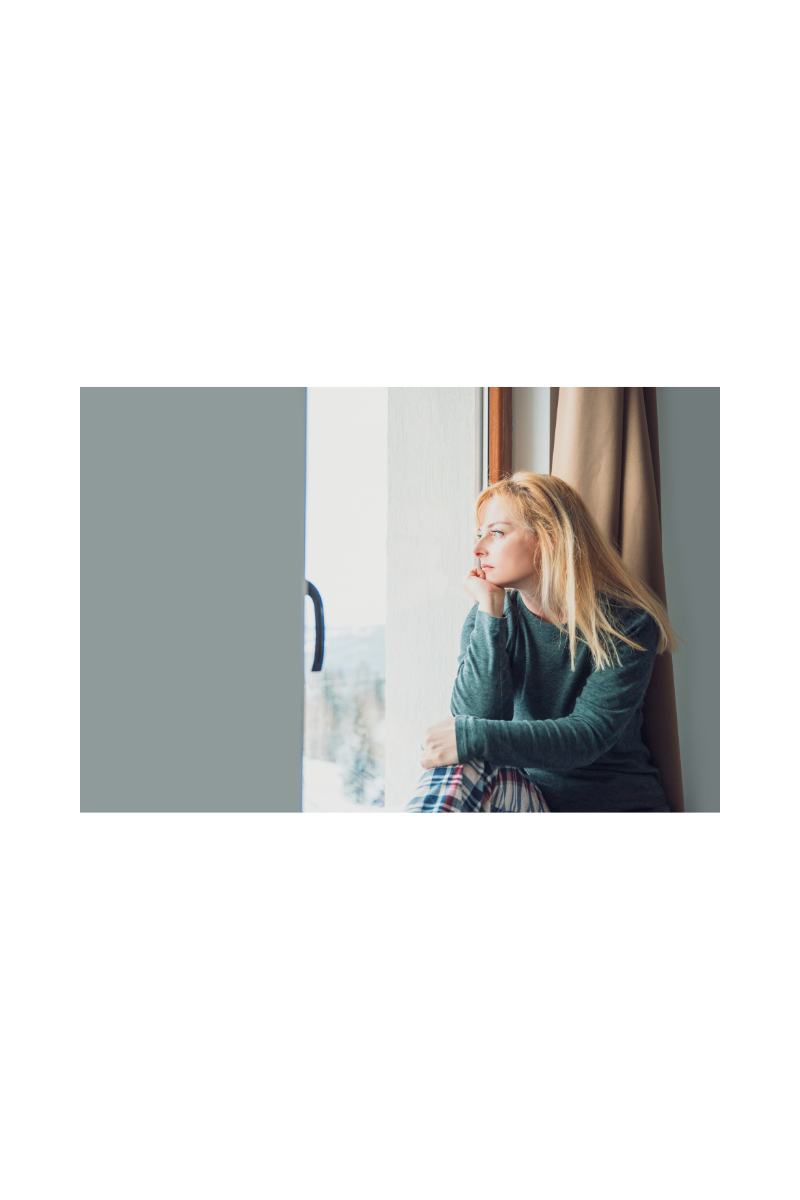 woman sitting on window sill looking outside