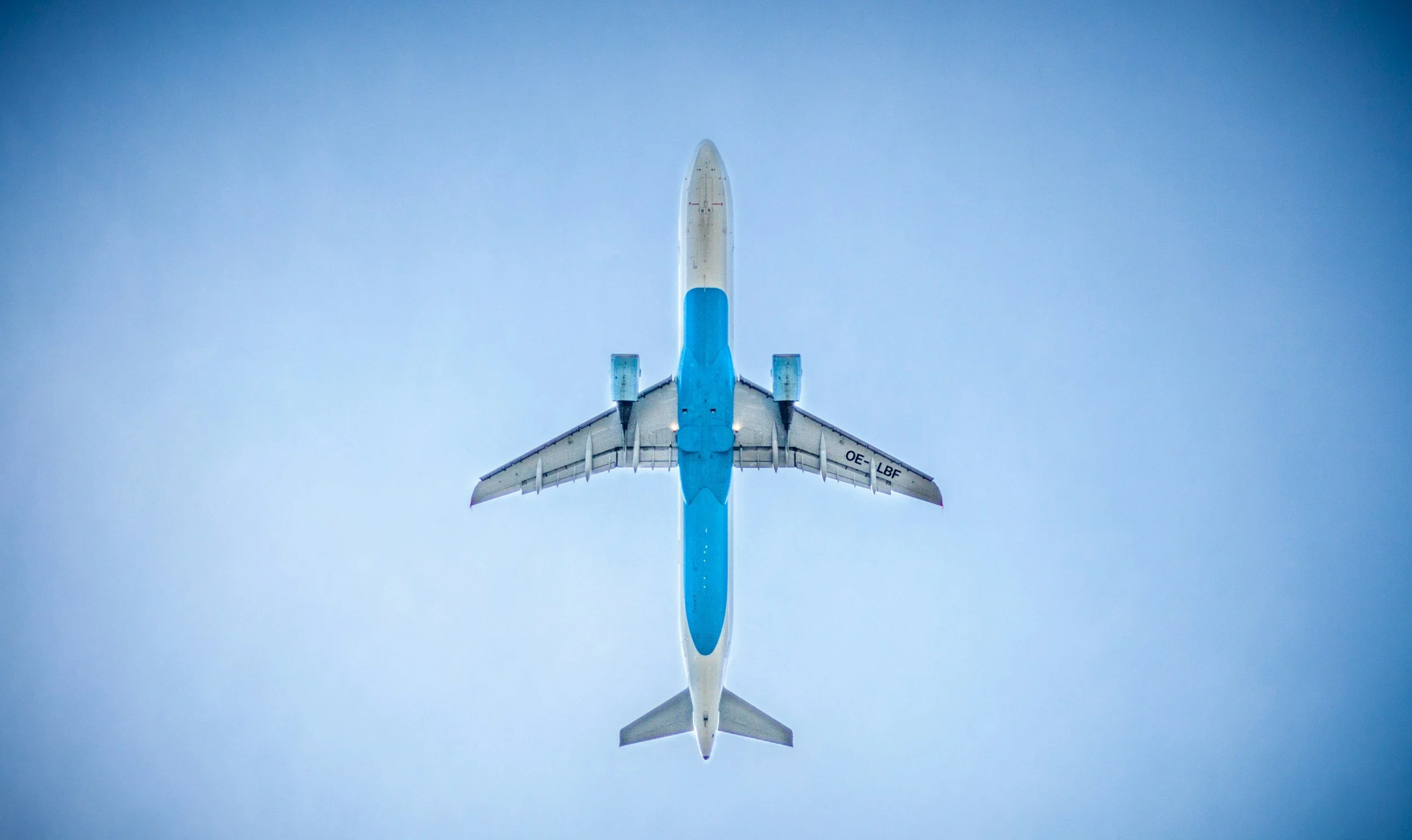 An airplane viewed from directly below flying in a clear sky.