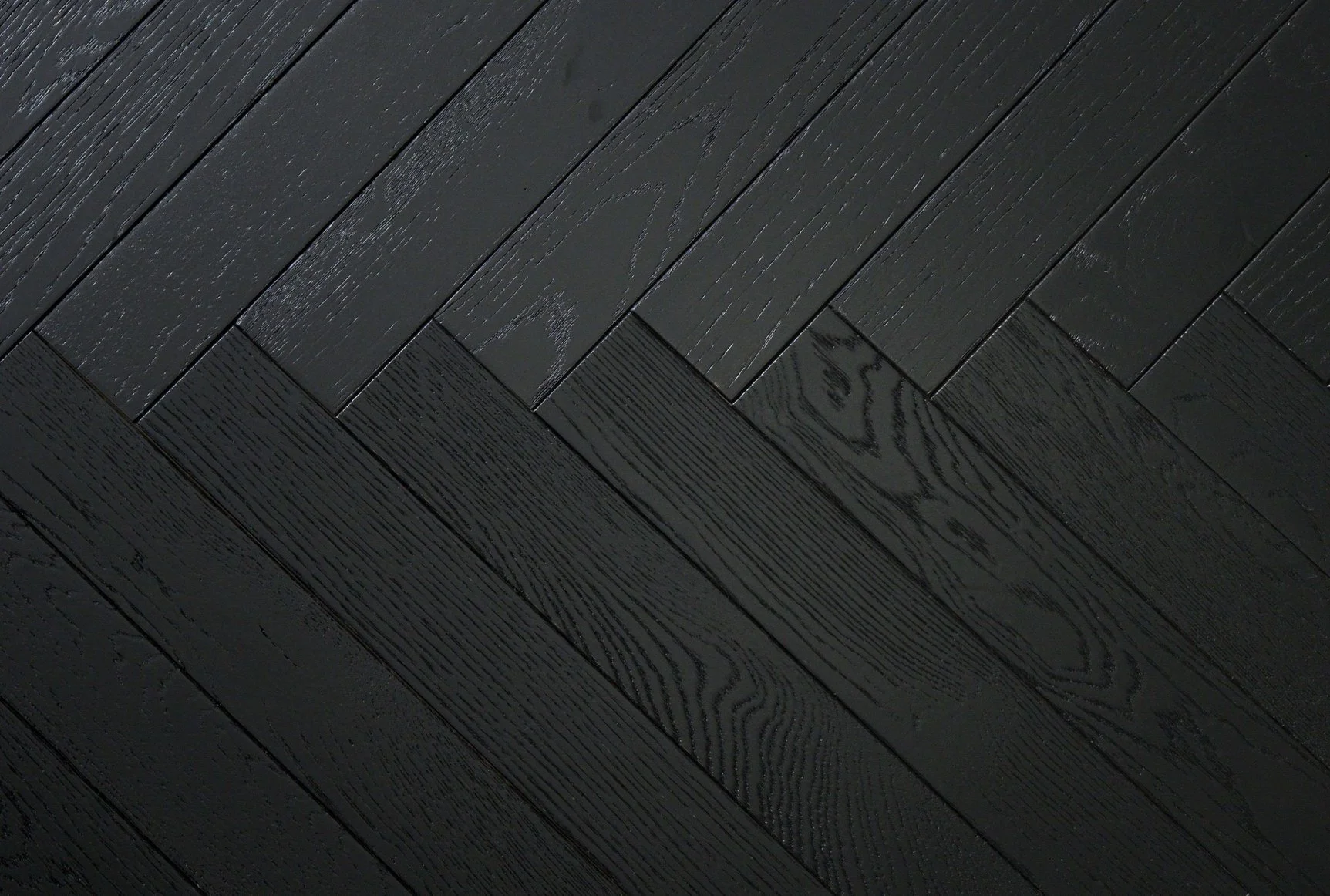 Superficie de suelo de madera pintada de negro en disposición en espiga