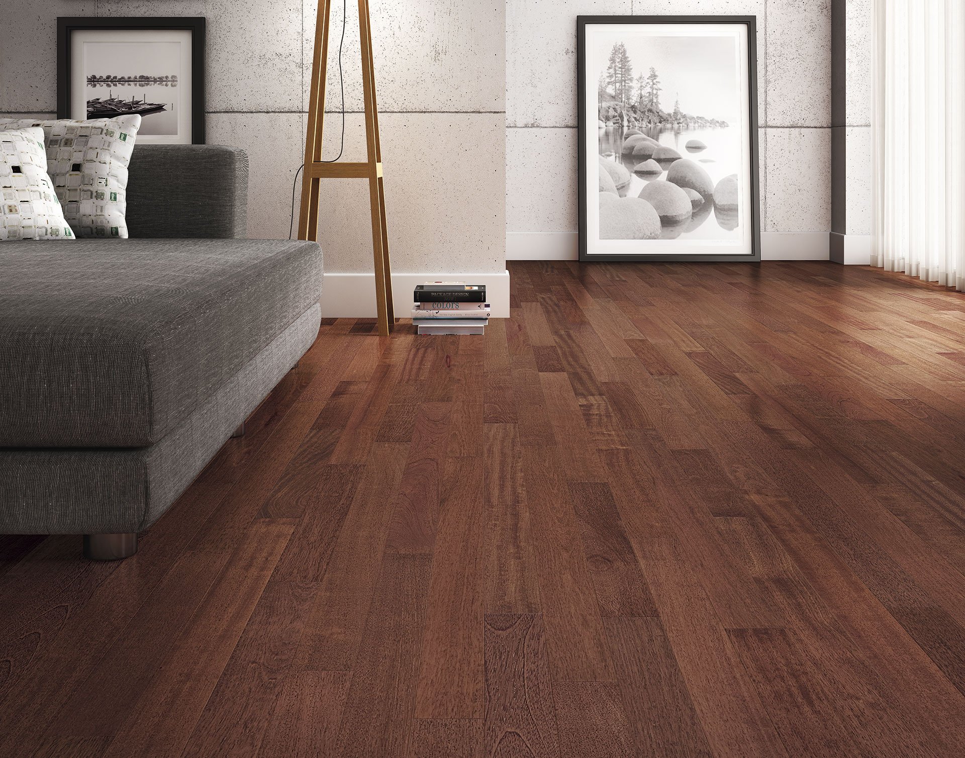 Sala de estar con piso de madera, sofá gris, dos cuadros tapizados, una estantería de madera, y un ventanal con cortinas blancas.
