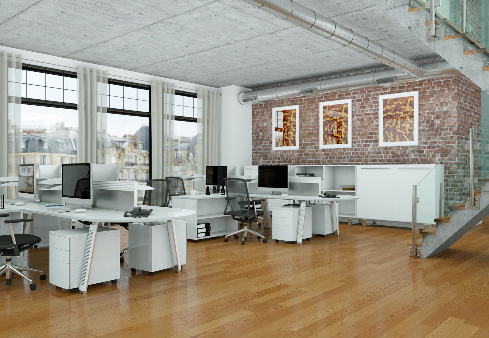 Oficina moderna con escritorios blancos, sillas de oficina, computadoras, paredes de ladrillo expuesto, arte enmarcado en la pared, ventanas grandes con cortinas blancas, piso de madera, escaleras de metal y vidrio, tuberías expuestas en el techo.